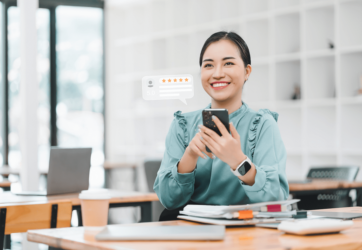 Woman smiling with smartphone at desk