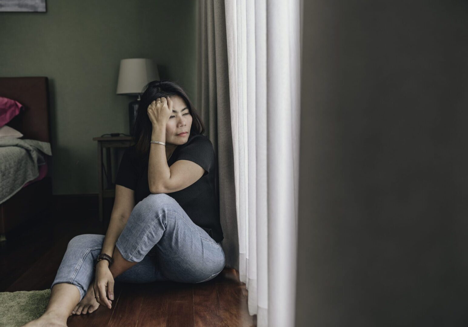 sad and depressed woman sitting alone at home on the floor