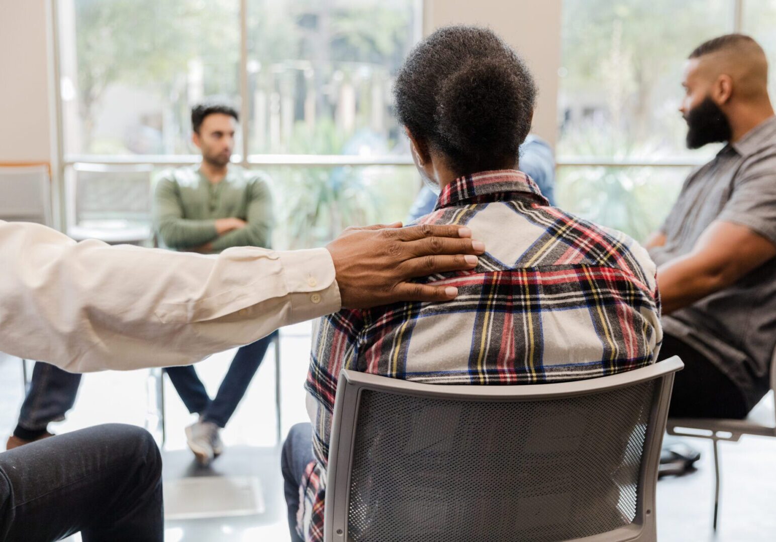 A therapist comforts a patient during a group therapy session. Mental health support and emotional wellbeing.